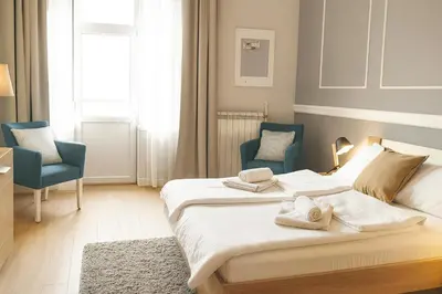 a bedroom with two beds and two blue chairs at City Break Apartments - City Zen in Belgrade
