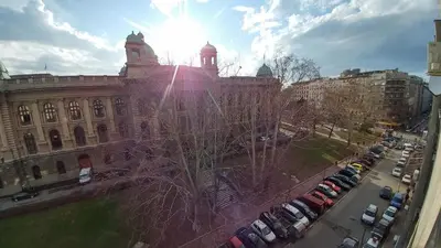 a large building with cars parked in a parking lot at Balkan-inn Parlament apartment in Belgrade