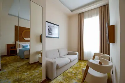 a living room with a couch and a mirror at Hotel City Savoy in Belgrade