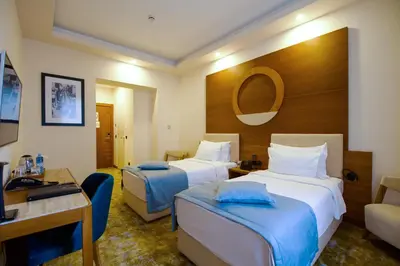 a hotel room with two beds and a desk at Hotel City Savoy in Belgrade