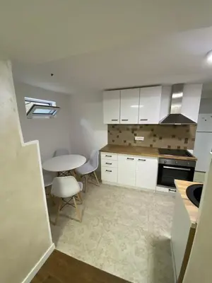 a kitchen with white cabinets and a table and chairs at Baron Apartment in Belgrade
