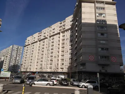 a large building with cars parked in a parking lot at Apartment Tifani Belville in Belgrade