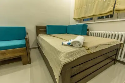 a small bedroom with a bed and two blue chairs at Apartments Jevremova in Belgrade