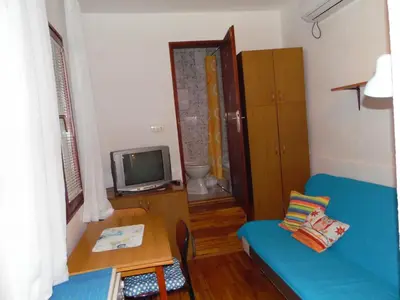 a living room with a blue couch and a tv at Studio Kalenic in Belgrade