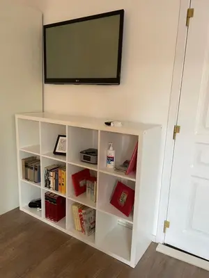 a white book shelf with a television on a wall at Slavija Square Apartments in Belgrade