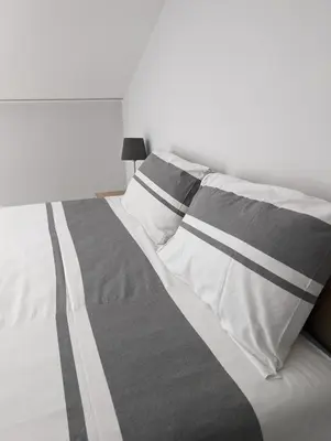 a white bed with gray and white sheets and pillows at Top Belgrade Apartments in Belgrade