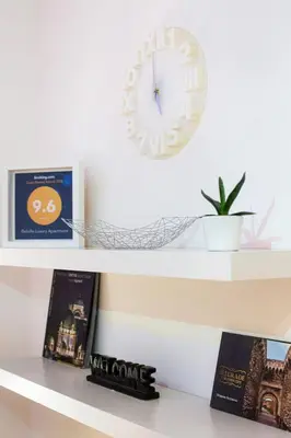 a clock on a wall above a shelf with books at Belville Luxury Apartment in Belgrade