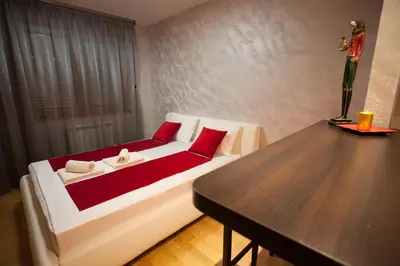 a bedroom with a white bed with red pillows and a table at Gentleman Dog Apartment in Belgrade