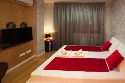 a bedroom with a large white bed with red pillows at Gentleman Dog Apartment in Belgrade
