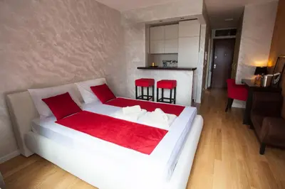 a white bed with red pillows in a room at Gentleman Dog Apartment in Belgrade