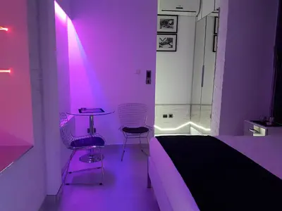 a bedroom with purple lighting and a bed and two chairs at Monroe Apartment in Belgrade