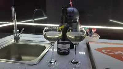 two glasses of white wine sitting next to a sink at Monroe Apartment in Belgrade