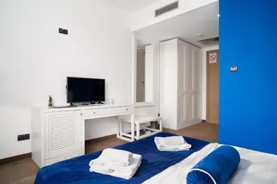 a white bedroom with a bed with a tv on it at Passport Belgrade in Belgrade