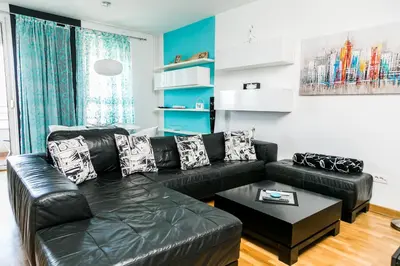 a living room with a black leather couch and a table at Twin Belville Apartments in Belgrade