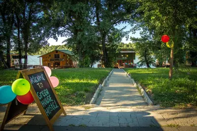 a sidewalk with a sign and balloons in the grass at Green House Hostel in Belgrade