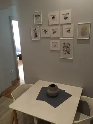 a white table with a hat on a wall with pictures at L9 Top Central Rooms and Apartments 2 in Belgrade