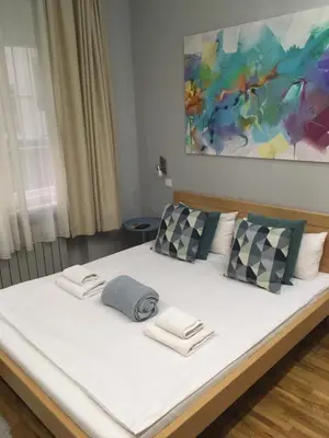 a large white bed with two pillows and a painting at L9 Top Central Rooms and Apartments 2 in Belgrade
