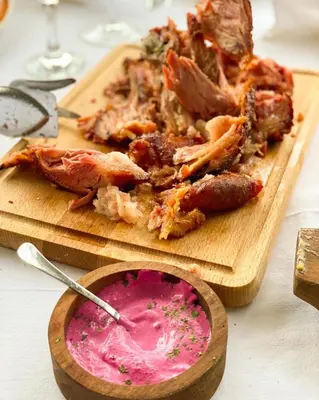 a wooden cutting board with meat and a bowl of pink dip at Kaštel Ečka in Ečka