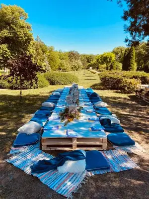 a long table with blue umbrellas in a field at Kaštel Ečka in Ečka