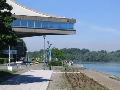 a building with a walkway next to a river at Danube Apartment in Belgrade