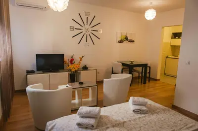 a living room with a table and a clock on the wall at Maja Apartment in Belgrade