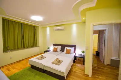 a bedroom with a large bed and a green curtain at Apartment Sweet House Politika in Belgrade