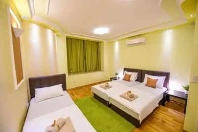 a bedroom with two beds and a green window at Apartment Sweet House Politika in Belgrade