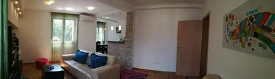 a living room with a couch and a painting on the wall at Shumice Apartment in Belgrade