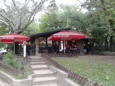 a restaurant with red umbrellas in a park at Shumice Apartment in Belgrade