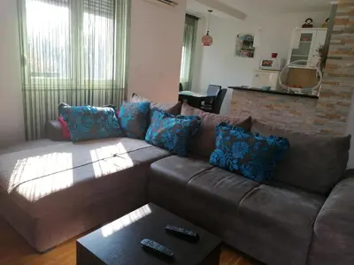 a living room with a brown leather couch with blue pillows at Shumice Apartment in Belgrade