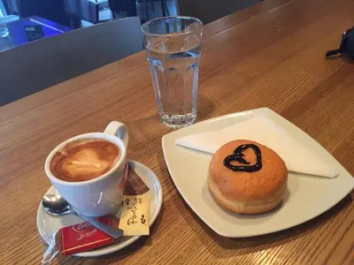 a donut and a cup of coffee on a table at Shumice Apartment in Belgrade