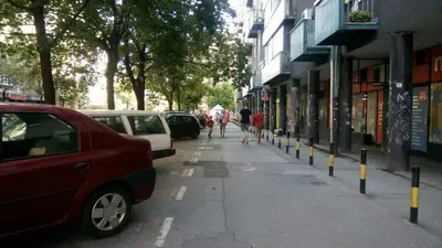 a street with parked cars and people walking down the sidewalk at Apartment Zindan in Belgrade