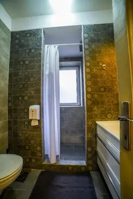 a bathroom with a shower and a toilet and a window at Panorama Central Apartments in Belgrade