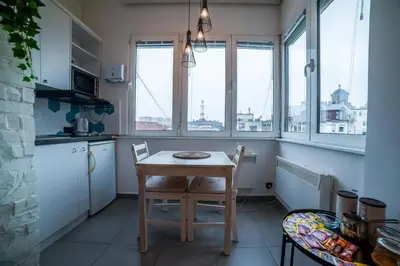 a kitchen with a table and chairs and windows at Panorama Central Apartments in Belgrade