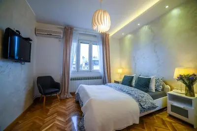 a bedroom with a bed and a tv and a window at Panorama Central Apartments in Belgrade