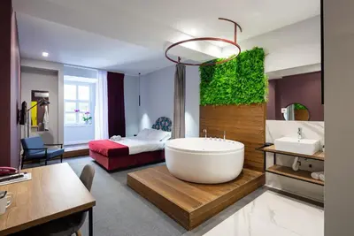 a bathroom with a large tub and a bedroom at Hotel Bohemian Garni - Skadarlija in Belgrade