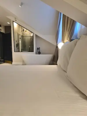 a large white bed with a bath tub in a room at Hotel Bohemian Garni - Skadarlija in Belgrade