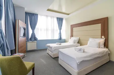 a hotel room with two beds and a chair at Privilege Suites by Central Park in Belgrade