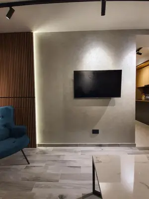 a living room with a blue chair and a television on a wall at Privilege Suites by Central Park in Belgrade