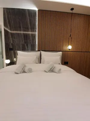 a large white bed with three pillows on it at Privilege Suites by Central Park in Belgrade