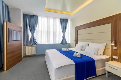 a bedroom with a large bed with blue curtains at Privilege Suites by Central Park in Belgrade