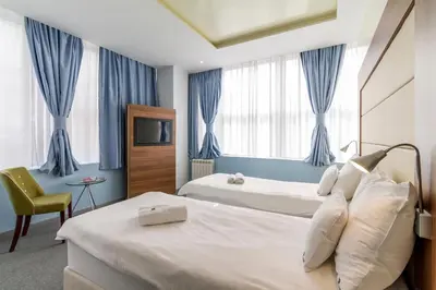 a hotel room with two beds and a chair at Privilege Suites by Central Park in Belgrade