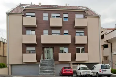 a building with two cars parked in front of it at Lazic Apartment in Belgrade
