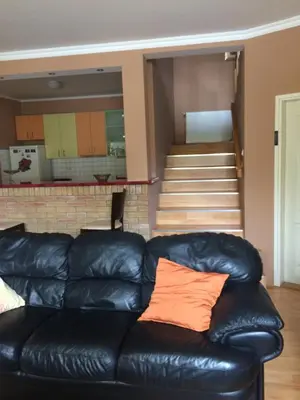 a black leather couch in a living room with stairs at Aleksandar Apartment in Pančevo