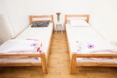 two twin beds in a room with a wooden floor at Hostel Jellostone in Belgrade