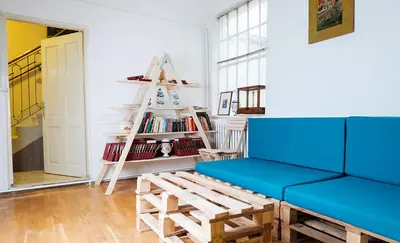 a living room with a blue couch and a book shelf at Hostel Jellostone in Belgrade