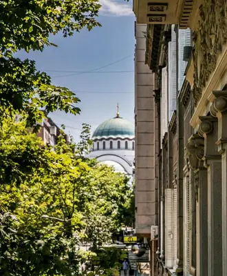 a domed building in the background of a street with trees at SAINT TEN Boutique Hotel, Small Luxury Hotels in Belgrade