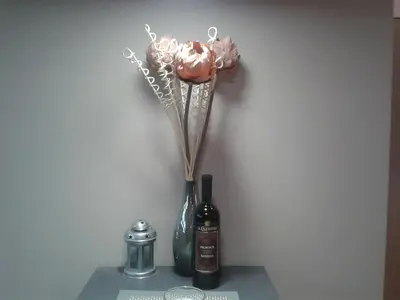 a vase with flowers next to a bottle of wine at Blue Danube Apartment in Belgrade