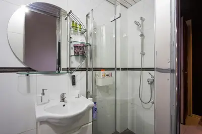a white bathroom with a sink and a shower at Princ Apartment in Belgrade