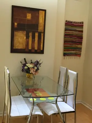 a glass table with white chairs and a vase of flowers at AMN Center Apartment in Belgrade